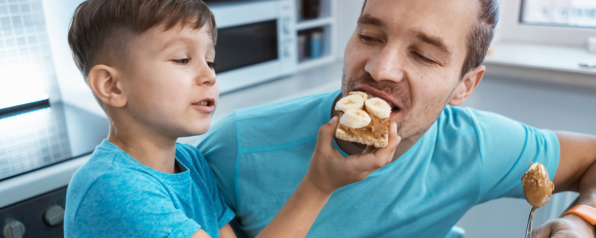 a child feeding a snack to a man