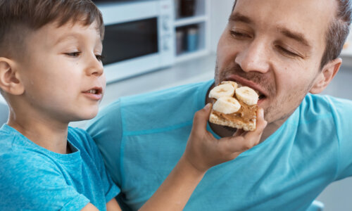 a child feeding a snack to a man